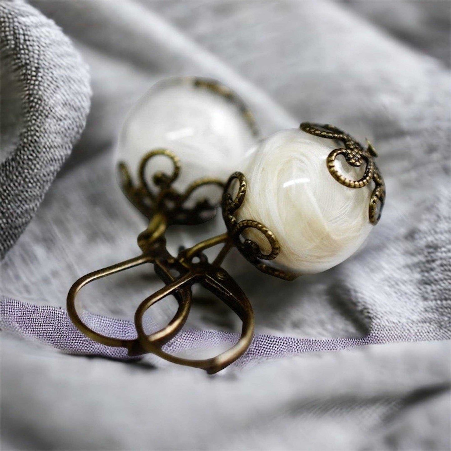 Detailfoto van glazen bol oorbellen met bronzen ornamenten, lichtgewicht sieraden