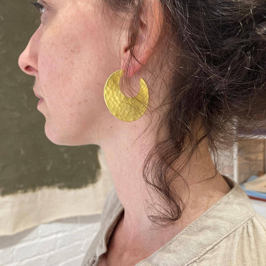 Gouden oorbellen met maanfomige design gedragen door een vrouw voor sieraden