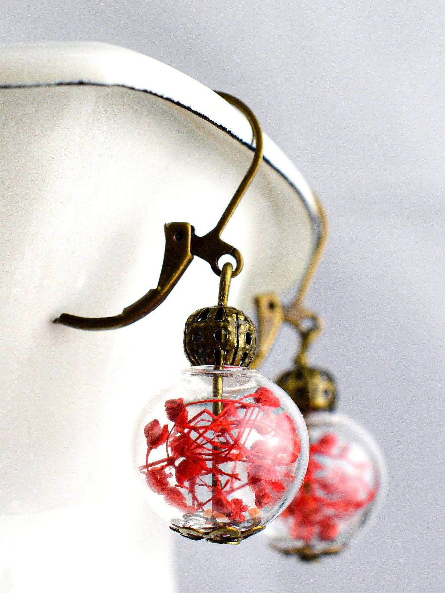 Close-up van vintage oorbellen met gedroogde bloemen en koper, handgemaakt, uniek, RAAK.Oorringen BLOESEM ROOD