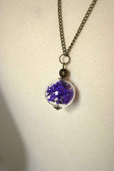 Halsketting met glazen bol en droogbloemen, gedragen als sieraad