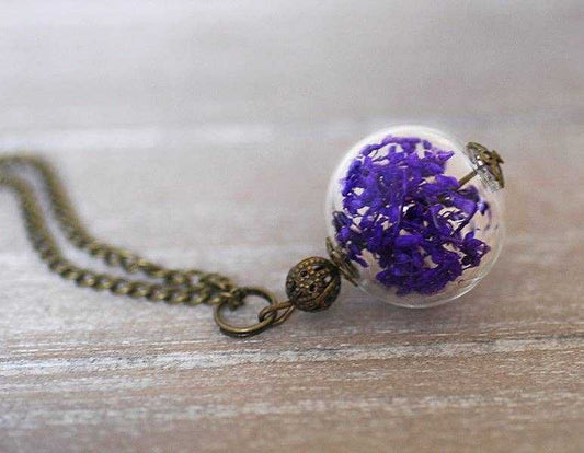 Close-up van droogbloemen halsketting met glazen bol en bronzen details