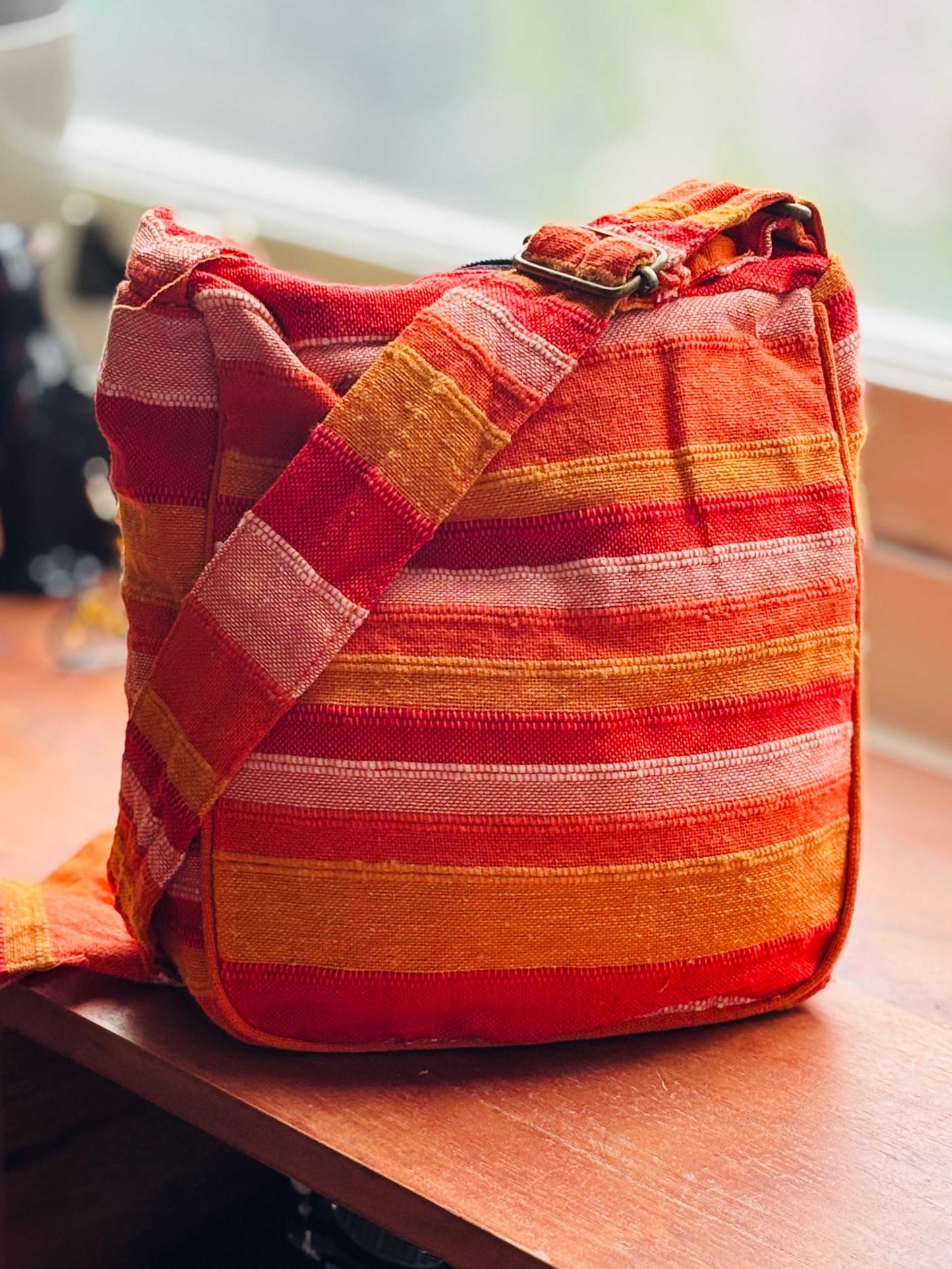 Kleurrijke handtas met stripes en verstelbare band op houten tafel