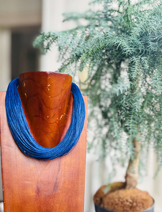 kleurige gewaxt katoen halsketting met blauwe details op houten standaard