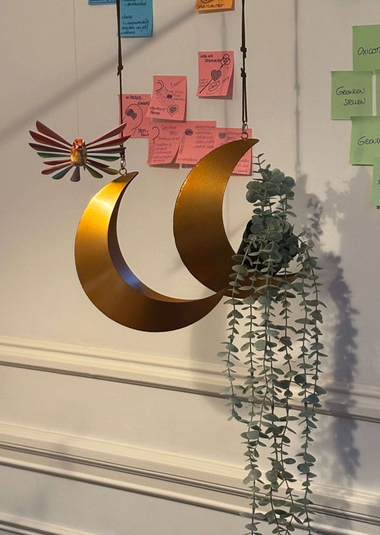 Goudkleurige metalen maanhanger met decoratief element en plantenhanger