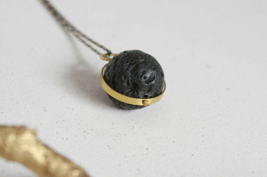 Close-up van lavasteen diffuser ketting met gouden rand en ketting