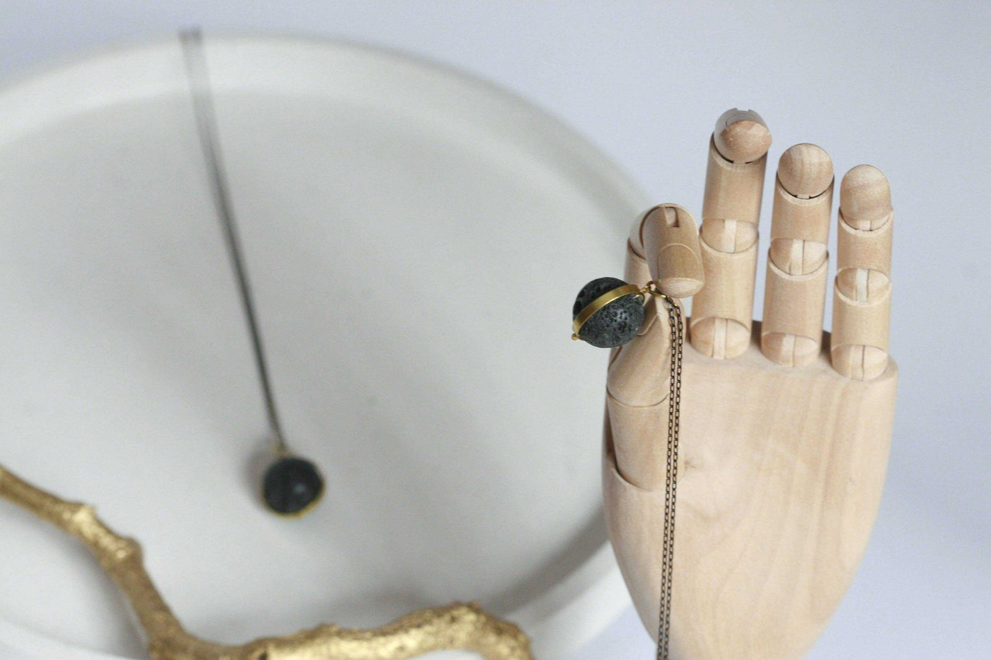 Lavasteen diffuser ketting met gouden rand gedragen op houten hand
