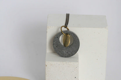 Beton ketting met gouden accent, op witte blok, minimalistisch en uniek