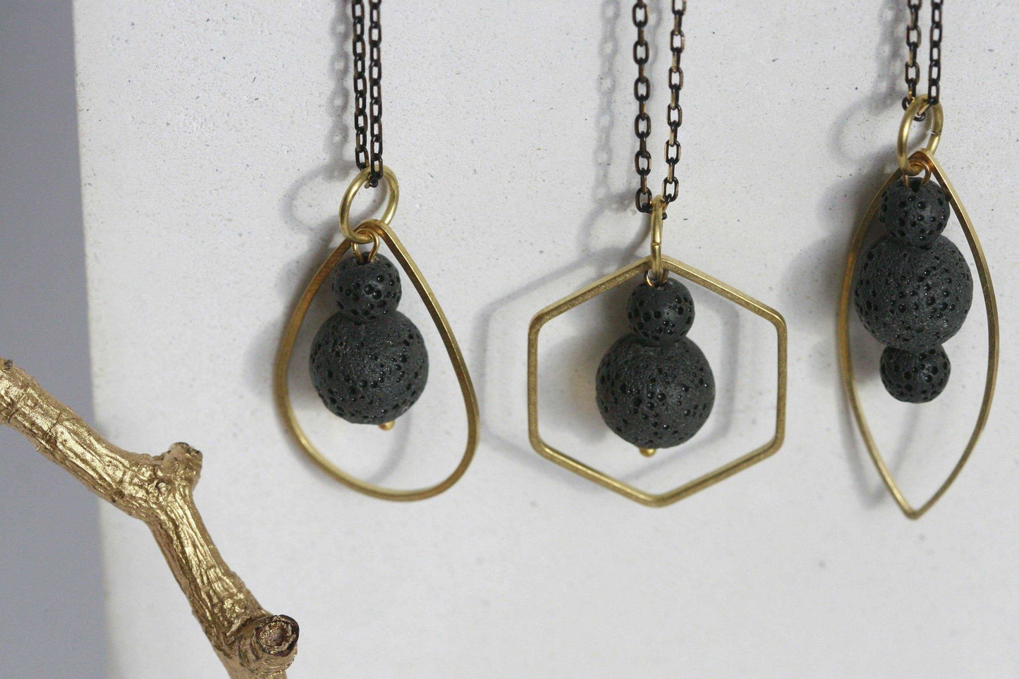 Close-up van zwart lavasteen diffuser ketting met gouden metalen frame, handgemaakt in Ierland