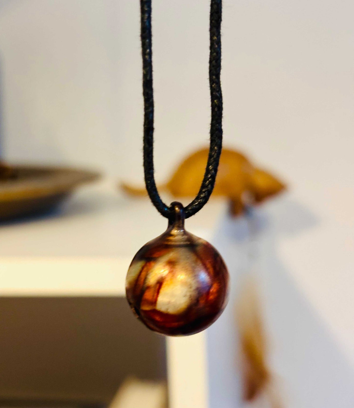 Geëmailleerde hanger met belletje aan zwart koord, uniek design