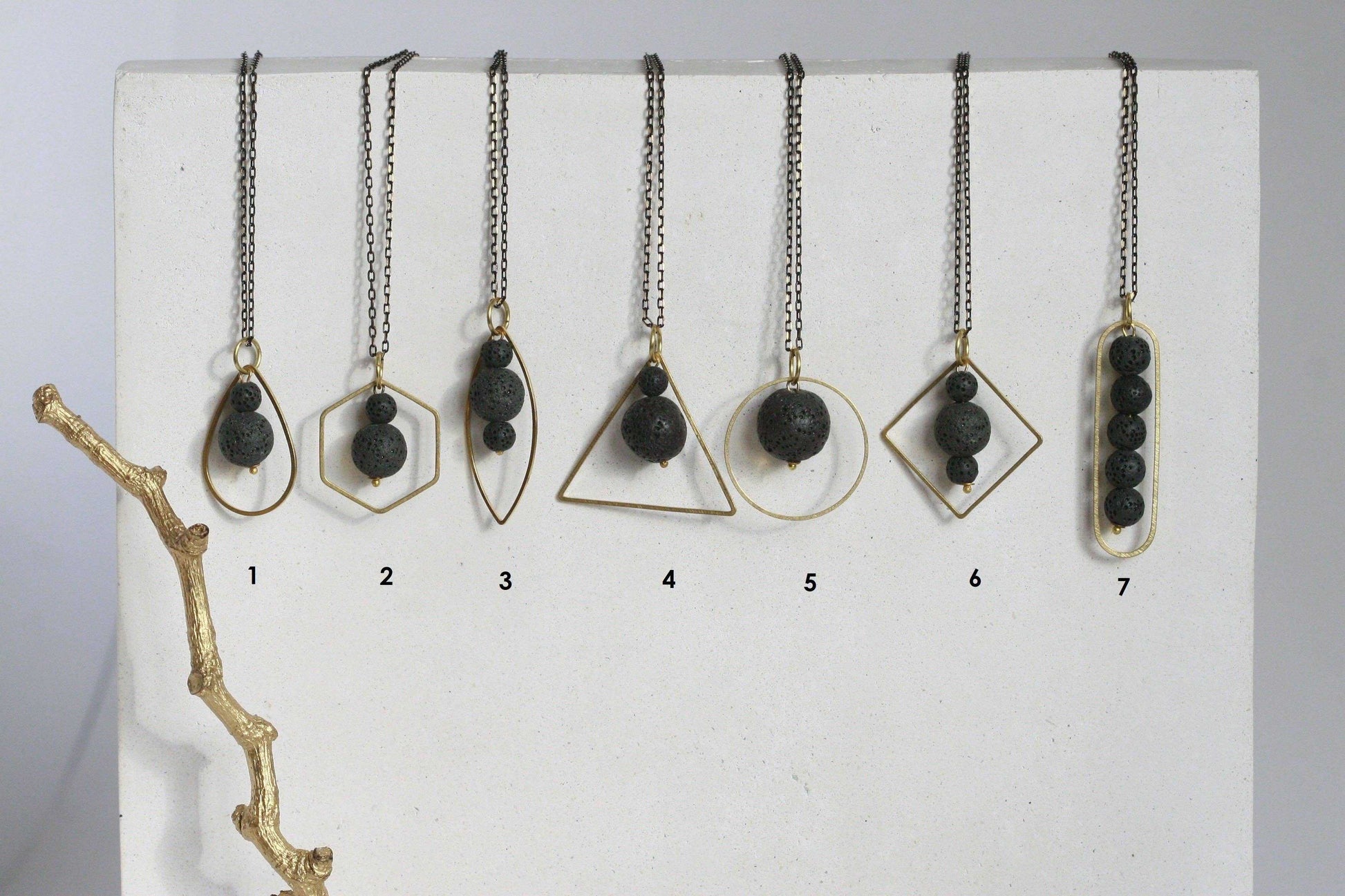 Zwart lavasteen diffuser ketting met geometrische gouden omlijsting, minimalistisch design