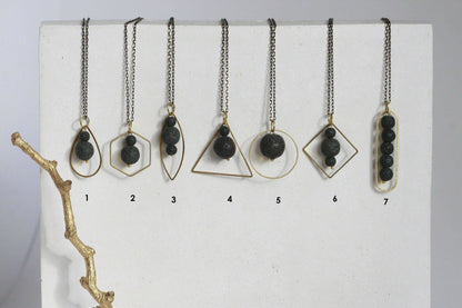 Zwart lavasteen diffuser ketting met geometrische gouden omlijsting, minimalistisch design